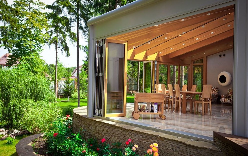 This is an example of a large transitional back porch design in Moscow with an awning.