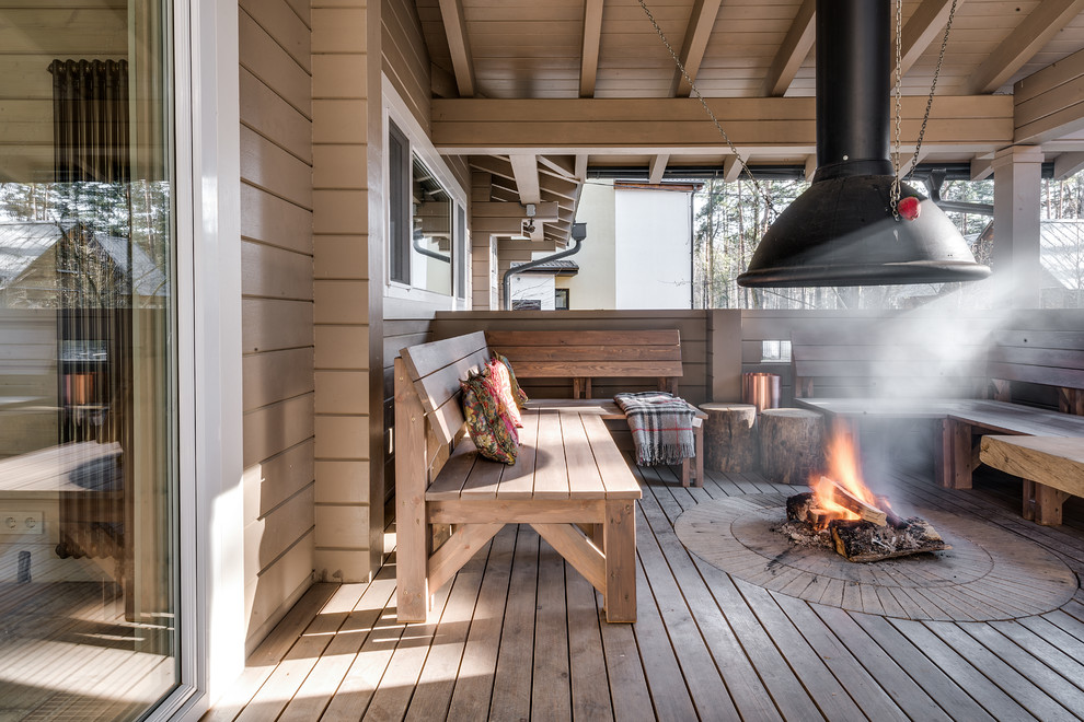 Aménagement d'un porche d'entrée de maison montagne avec un foyer extérieur, une extension de toiture et une terrasse en bois.