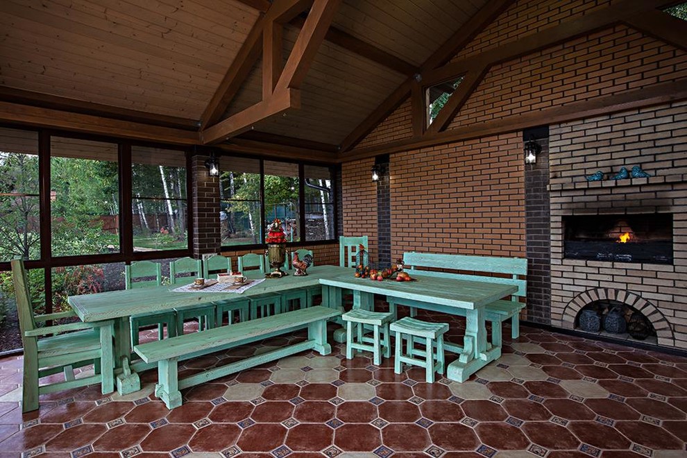 Modelo de terraza de estilo de casa de campo de tamaño medio en patio trasero con cocina exterior y adoquines de hormigón