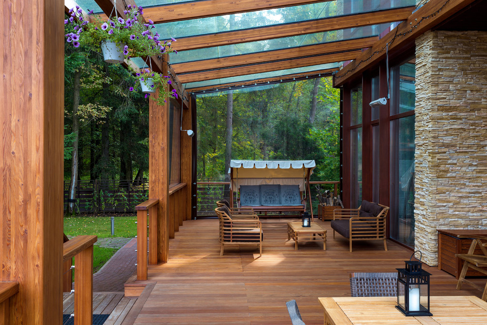 Cette photo montre un grand porche d'entrée de maison avant tendance avec une extension de toiture, une moustiquaire, des pavés en pierre naturelle et un garde-corps en bois.