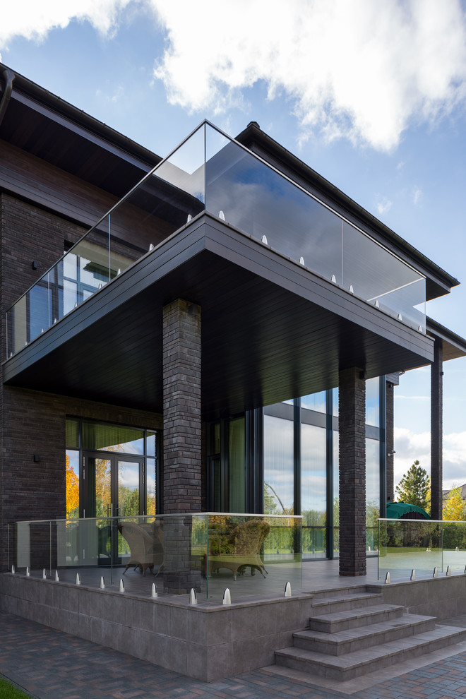 Idéer för stora industriella verandor på baksidan av huset, med naturstensplattor, takförlängning och räcke i glas