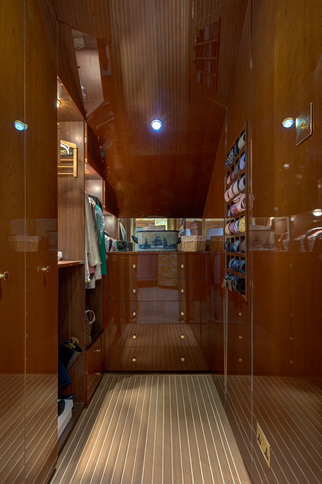 Foto de armario vestidor de hombre marinero de tamaño medio con armarios con paneles lisos, puertas de armario de madera oscura y suelo de madera en tonos medios