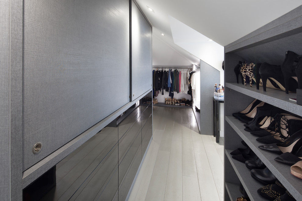 Design ideas for a large contemporary gender neutral dressing room in London with grey cabinets, open cabinets, light hardwood flooring and beige floors.