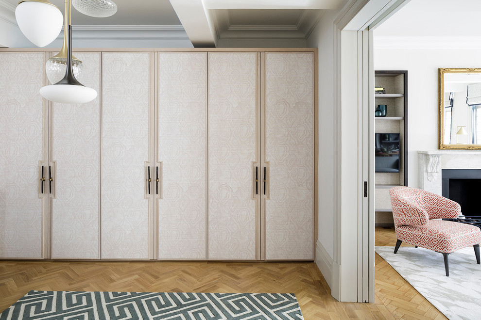 Large classic wardrobe in London with flat-panel cabinets, light hardwood flooring and beige floors.