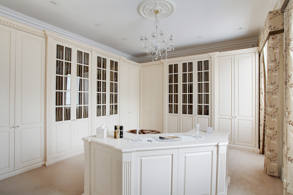 Exemple d'un très grand dressing room chic neutre avec un placard avec porte à panneau surélevé, des portes de placard blanches, moquette et un sol beige.