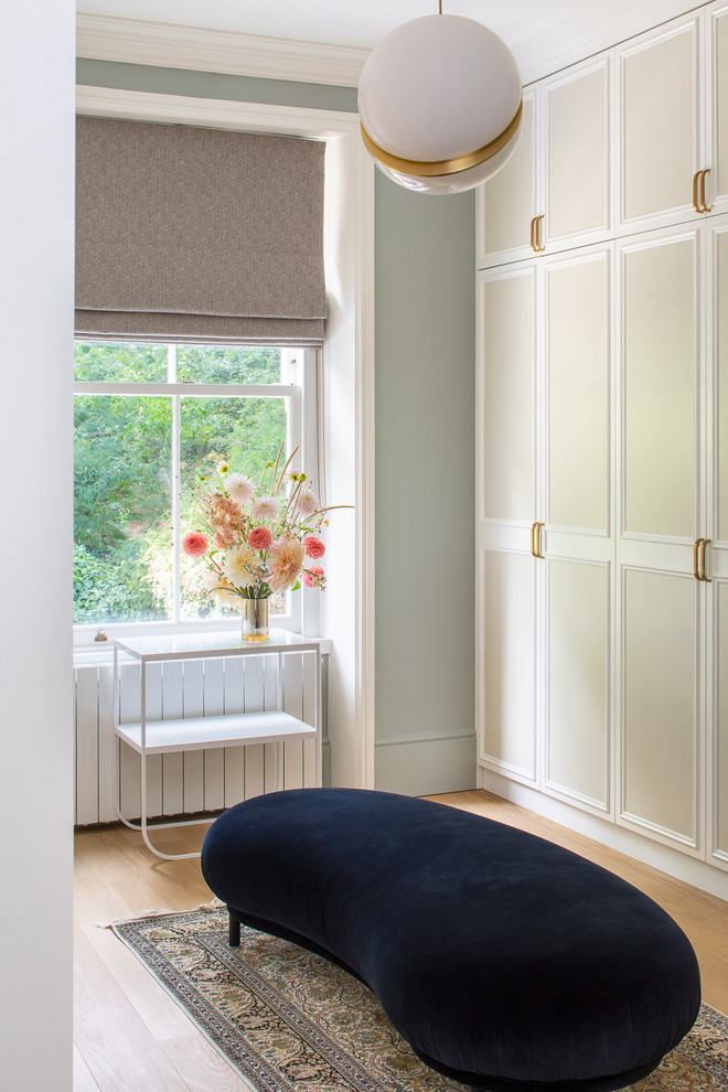 Inspiration for a classic walk-in wardrobe for women in London with recessed-panel cabinets, beige cabinets, medium hardwood flooring and brown floors.