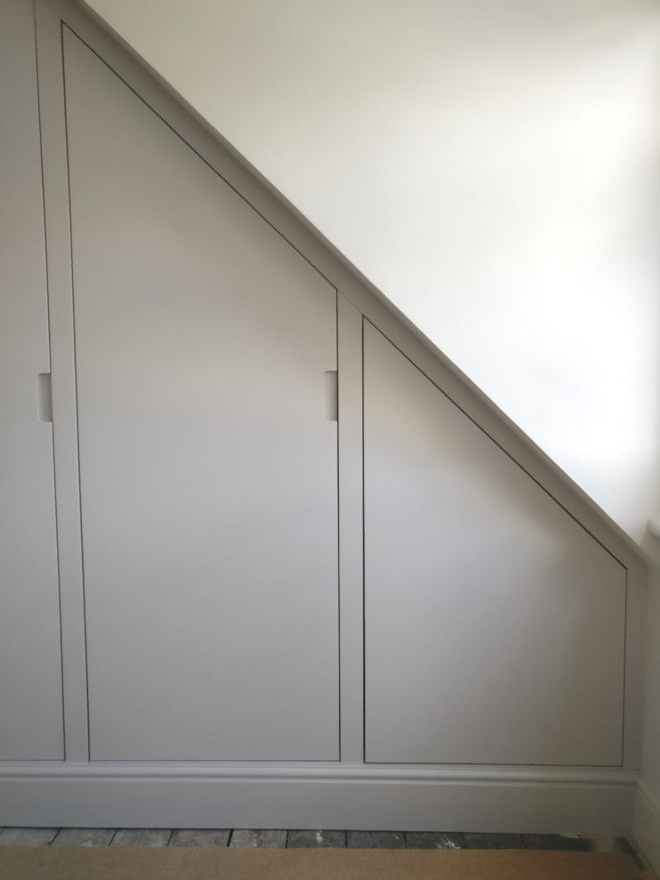 Cette photo montre une très grande armoire encastrée victorienne avec un placard à porte plane, des portes de placard blanches, moquette et un sol beige.