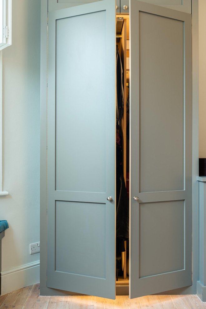 Cette image montre une grande armoire encastrée victorienne avec un placard avec porte à panneau encastré, des portes de placard grises, parquet clair et un sol marron.
