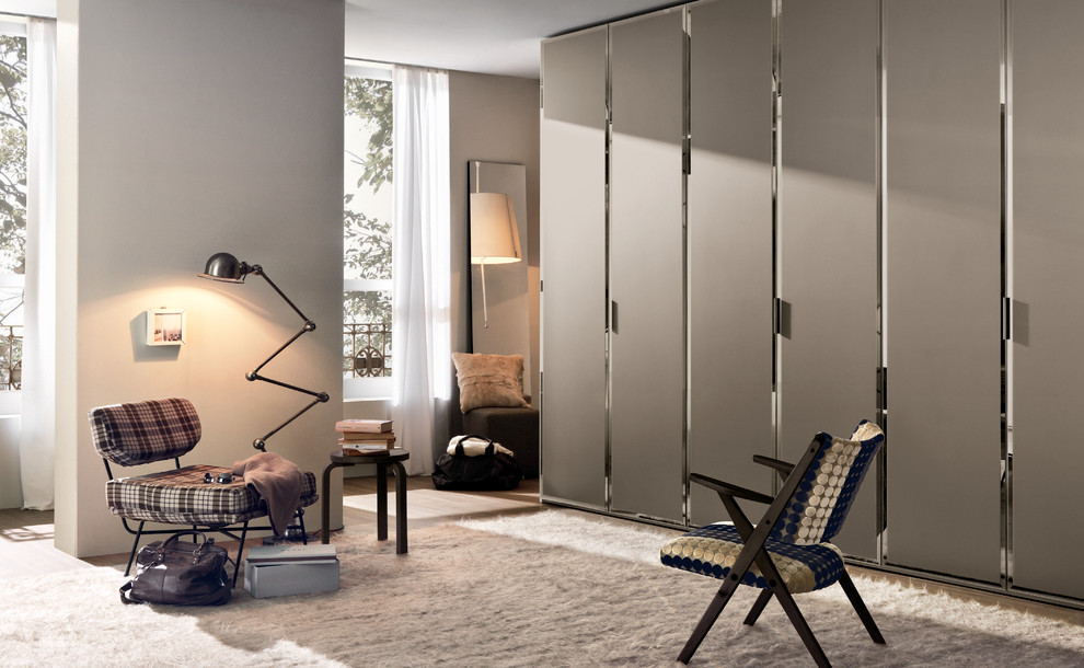 Imagen de vestidor unisex actual de tamaño medio con puertas de armario de madera oscura, suelo de madera en tonos medios y armarios con paneles lisos