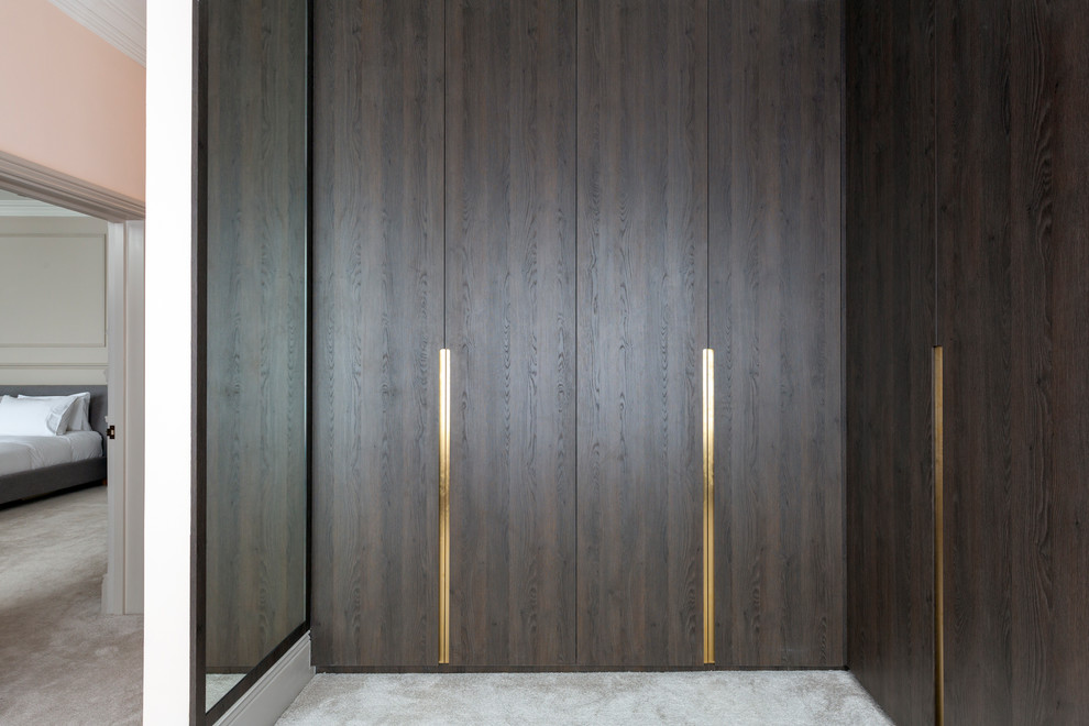 Cette photo montre un dressing tendance en bois foncé de taille moyenne avec un placard à porte plane, moquette et un sol gris.
