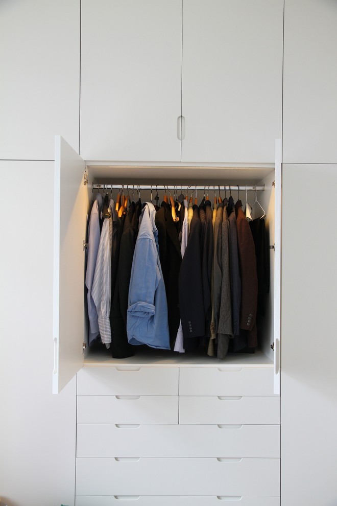 This is an example of a medium sized modern gender neutral standard wardrobe in London with flat-panel cabinets and white cabinets.