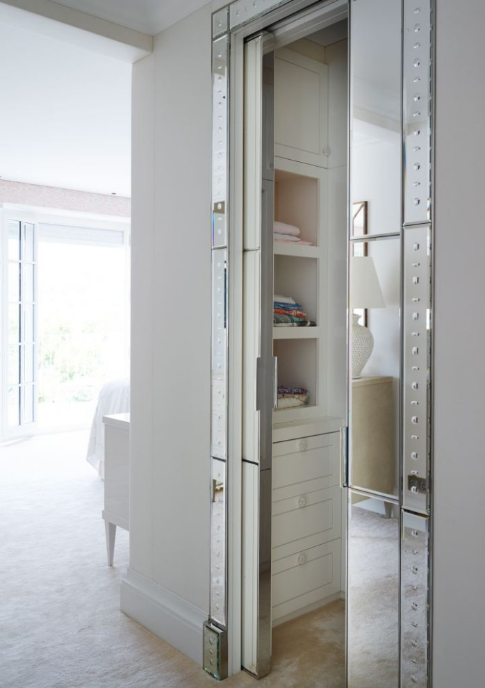 Foto di una piccola cabina armadio per donna design con ante di vetro, ante bianche, moquette e pavimento beige
