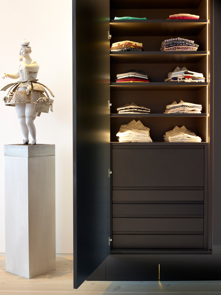 Photo of a medium sized contemporary gender neutral standard wardrobe in London with flat-panel cabinets, grey cabinets, light hardwood flooring and beige floors.
