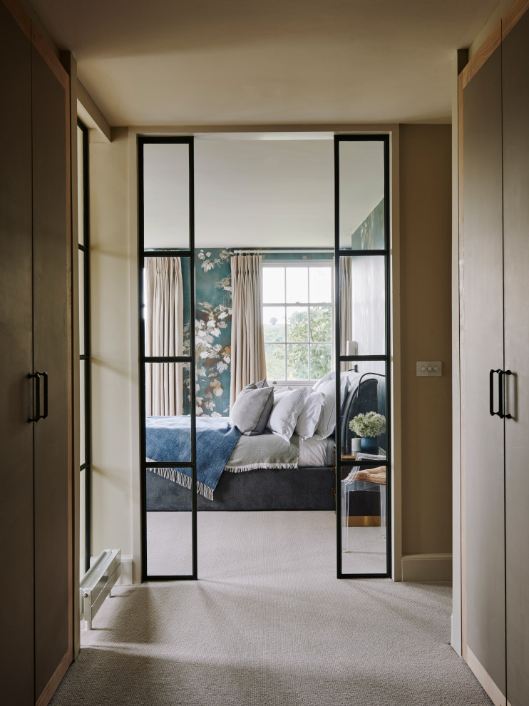 Пример оригинального дизайна: гардеробная комната среднего размера, унисекс в стиле неоклассика (современная классика) с плоскими фасадами, светлыми деревянными фасадами и ковровым покрытием