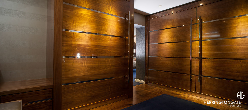 Neutrales Modernes Ankleidezimmer mit Ankleidebereich, hellbraunen Holzschränken und braunem Holzboden in Sonstige