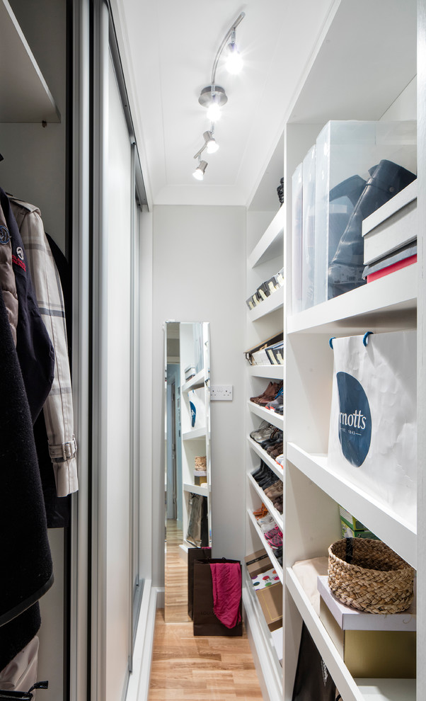 Small minimalist gender-neutral medium tone wood floor walk-in closet photo in Dublin with flat-panel cabinets and white cabinets