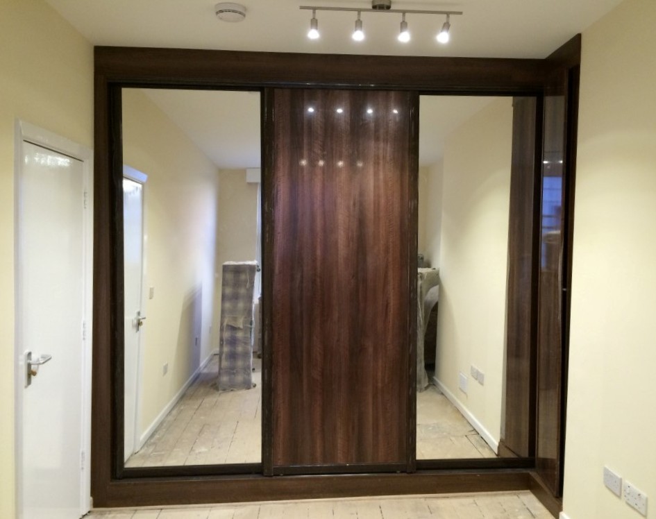 Ejemplo de armario unisex actual de tamaño medio con armarios tipo vitrina, puertas de armario de madera en tonos medios y suelo de madera clara