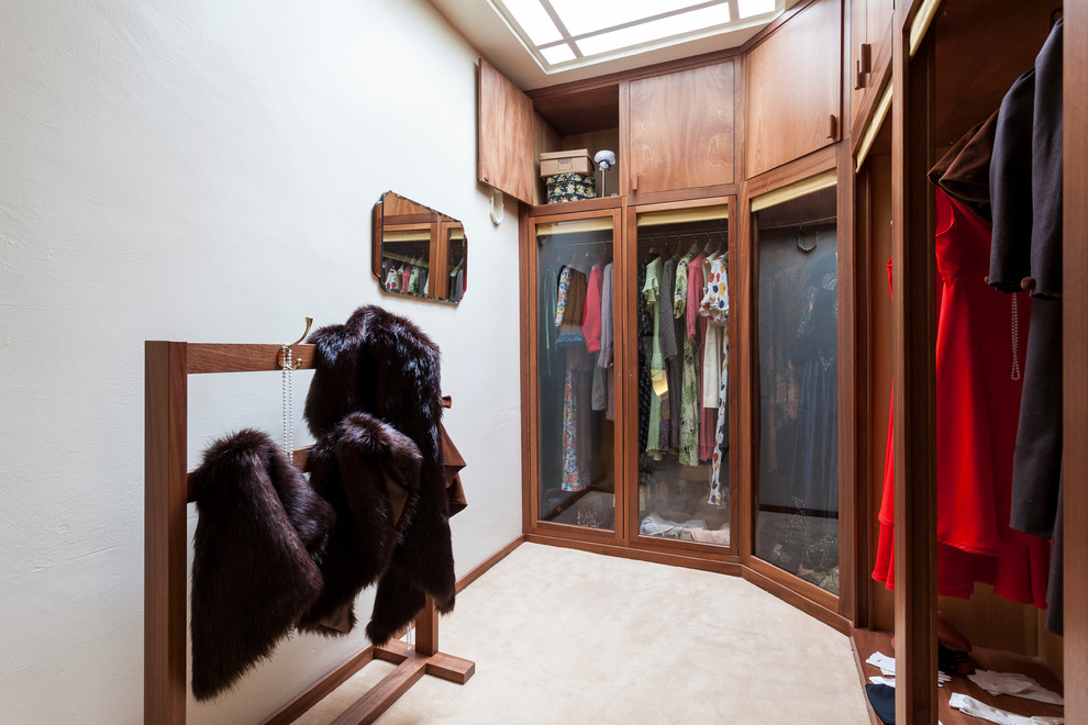 ロンドンにあるヴィクトリアン調のおしゃれなフィッティングルーム (ガラス扉のキャビネット、中間色木目調キャビネット、カーペット敷き) の写真