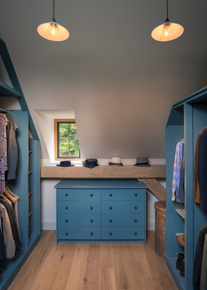 Diseño de armario vestidor unisex rural de tamaño medio con armarios abiertos, puertas de armario azules y suelo de madera en tonos medios