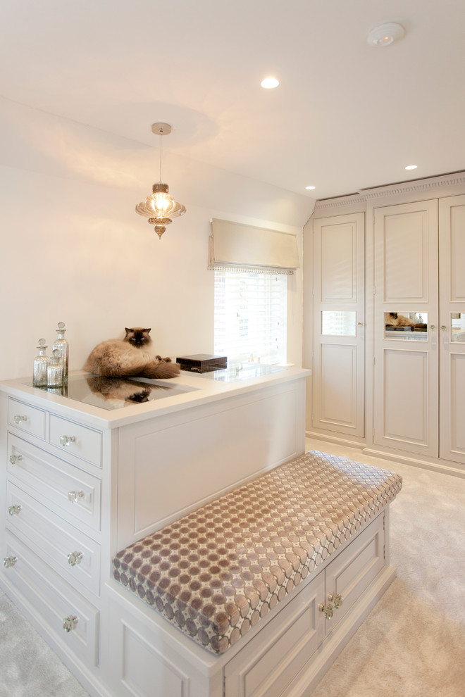 Classic walk-in wardrobe in Hampshire with beaded cabinets, beige cabinets and carpet.