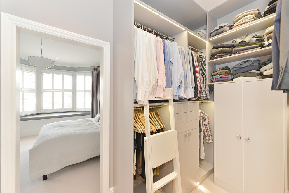 Modelo de armario vestidor unisex clásico renovado grande con armarios abiertos, puertas de armario de madera oscura, suelo de madera en tonos medios y suelo beige
