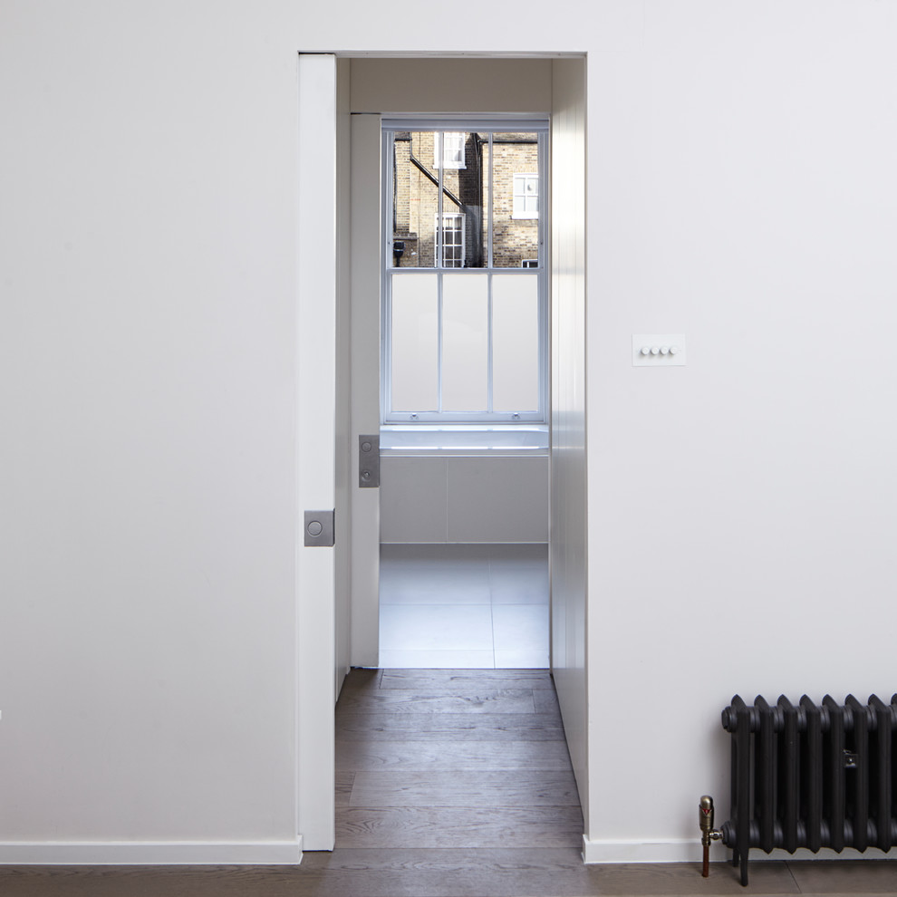 Ejemplo de armario vestidor unisex minimalista grande con armarios con paneles lisos, puertas de armario blancas, suelo de madera clara y suelo gris
