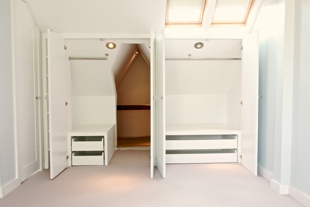 Example of a mid-sized trendy gender-neutral carpeted walk-in closet design in London with white cabinets