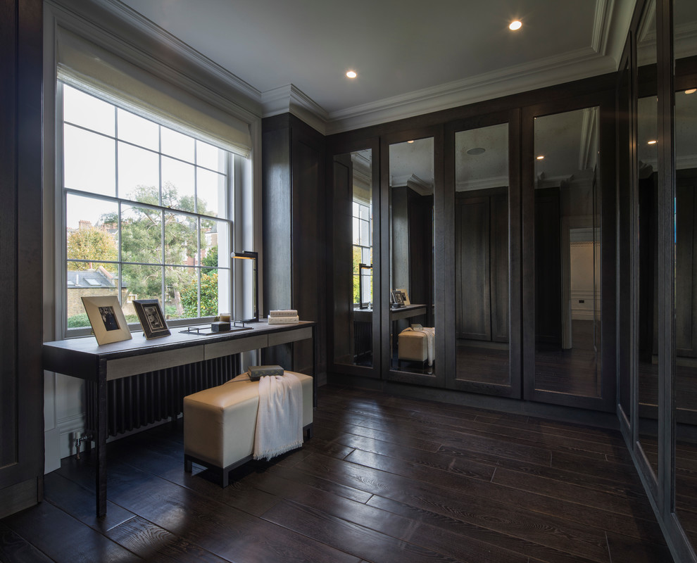 Inspiration for a medium sized traditional gender neutral dressing room in London with flat-panel cabinets, dark wood cabinets and dark hardwood flooring.