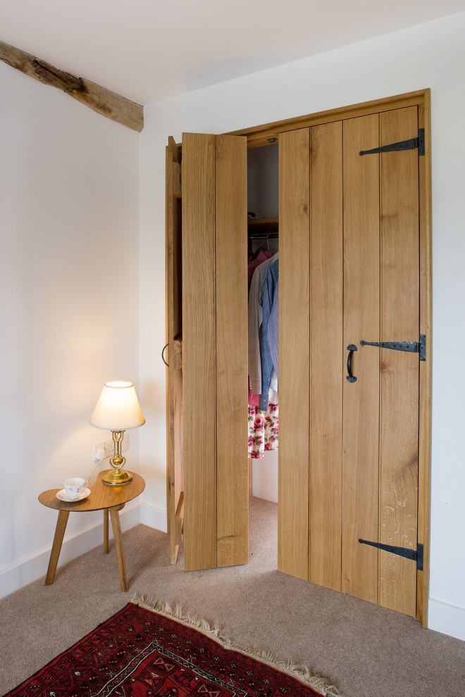 Diseño de armario y vestidor de estilo de casa de campo pequeño con armarios con paneles lisos, puertas de armario de madera oscura, moqueta y suelo beige