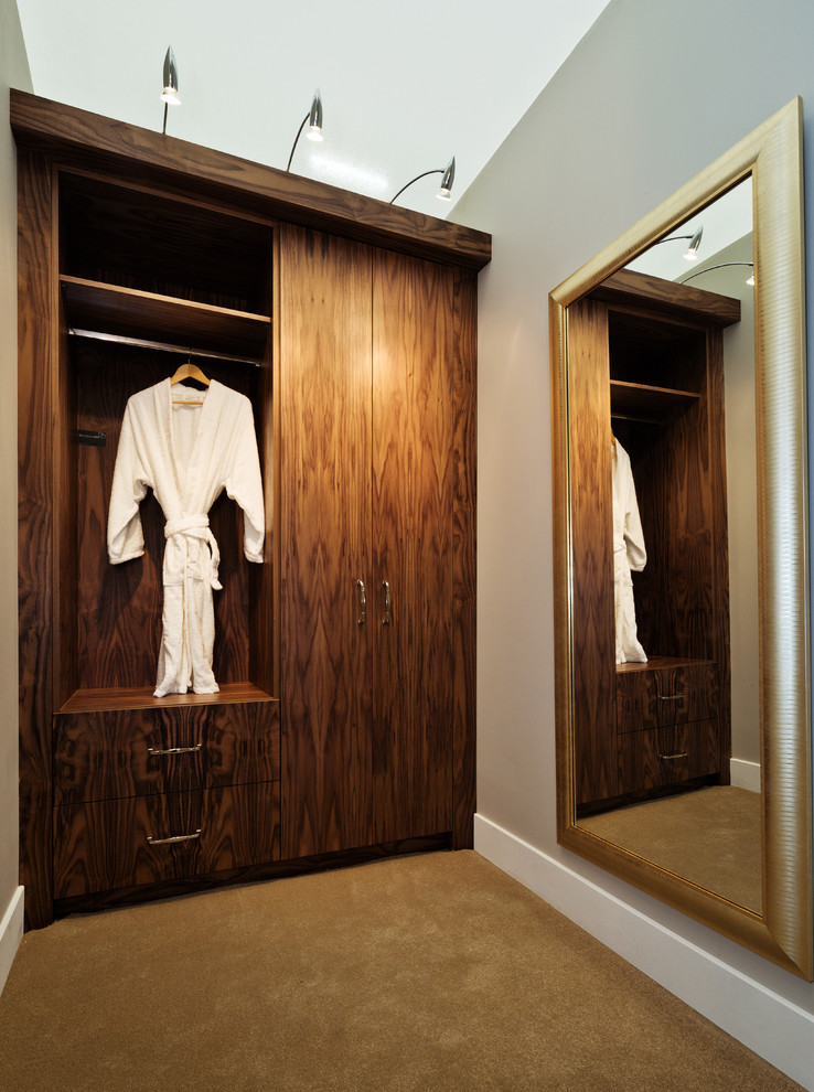 Foto di uno spazio per vestirsi unisex design di medie dimensioni con ante lisce, ante in legno scuro e moquette