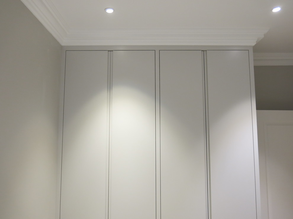 Imagen de vestidor unisex actual grande con armarios con paneles lisos y puertas de armario blancas