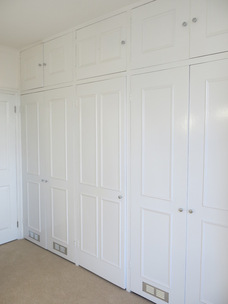 Modelo de armario vestidor unisex actual grande con armarios con rebordes decorativos, puertas de armario blancas, moqueta y suelo beige