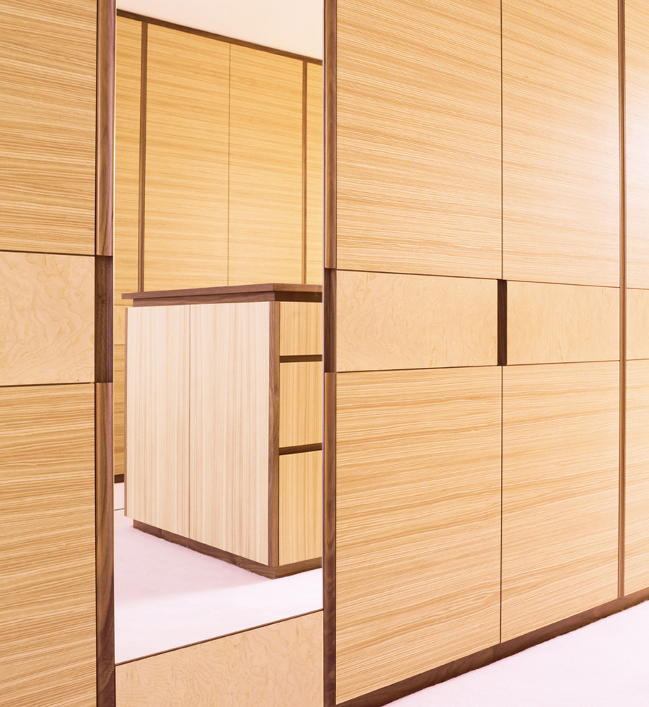 Inspiration pour un grand dressing minimaliste en bois brun neutre avec un placard à porte plane et moquette.