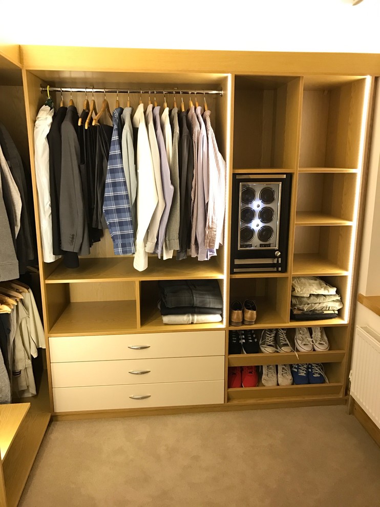 Large modern gender neutral walk-in wardrobe in Dublin with open cabinets and light wood cabinets.