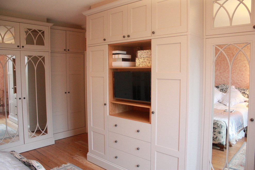 Example of a huge classic gender-neutral medium tone wood floor reach-in closet design in Other with shaker cabinets and gray cabinets