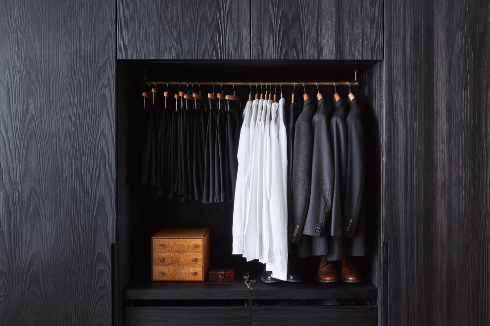 Großer Moderner Begehbarer Kleiderschrank mit flächenbündigen Schrankfronten, schwarzen Schränken und hellem Holzboden in London