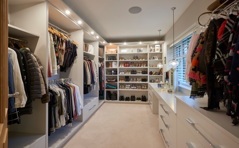 Immagine di uno spazio per vestirsi design di medie dimensioni con moquette, ante lisce, ante bianche e pavimento beige
