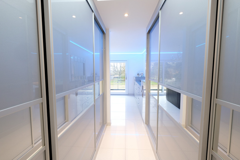 Mittelgroßes, Neutrales Modernes Ankleidezimmer mit Ankleidebereich, Glasfronten, beigen Schränken, Porzellan-Bodenfliesen und weißem Boden in Hertfordshire