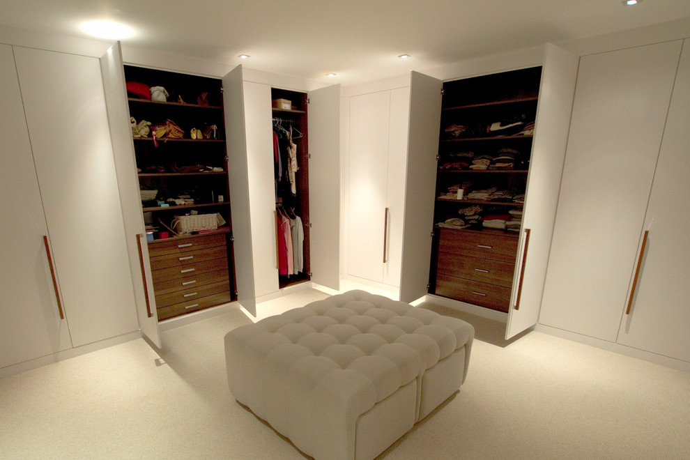 This is an example of a large modern gender neutral dressing room in London with flat-panel cabinets, white cabinets and carpet.