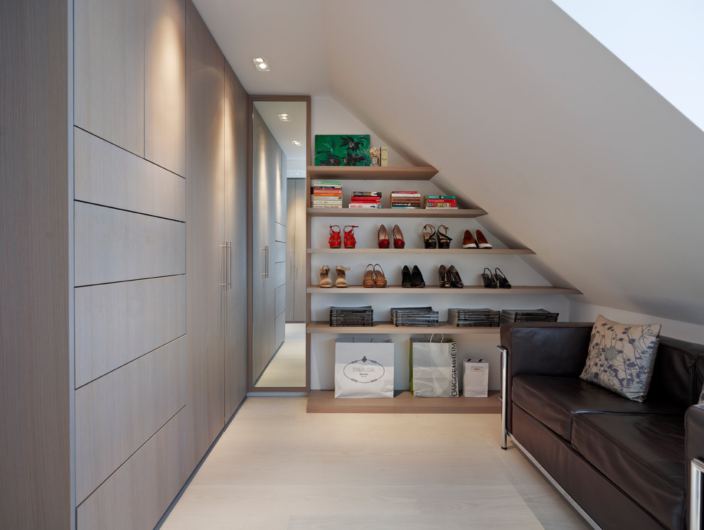This is an example of a contemporary gender neutral dressing room in London with flat-panel cabinets, light wood cabinets and light hardwood flooring.