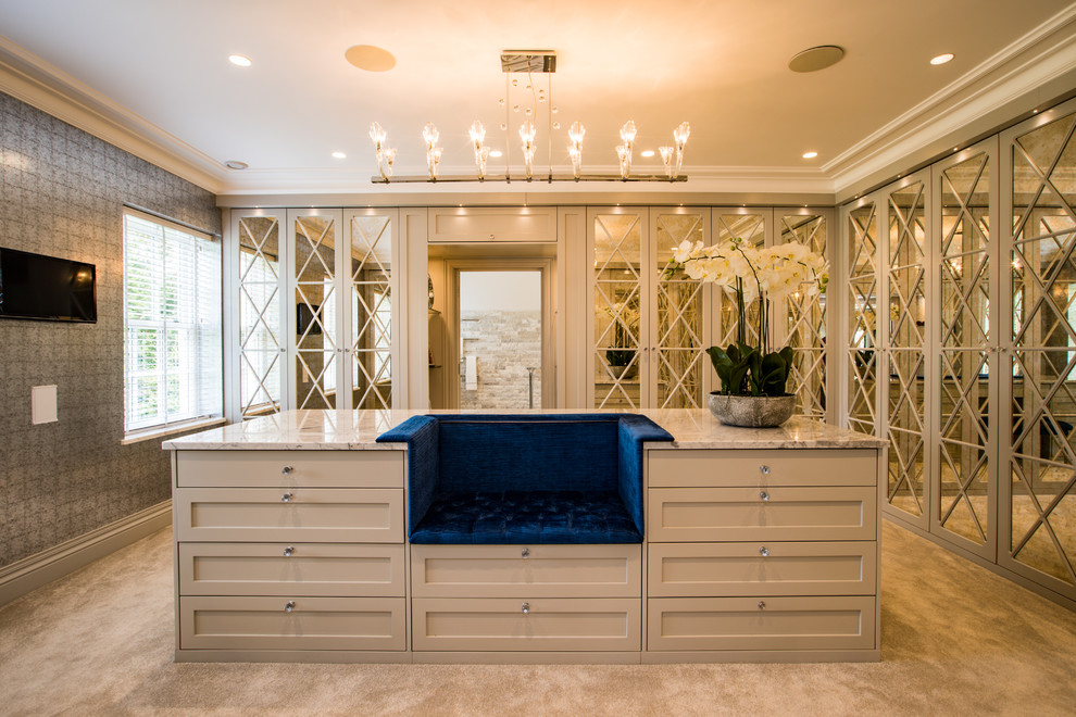 This is an example of a large contemporary gender neutral dressing room in Buckinghamshire with beige cabinets, carpet, beige floors and shaker cabinets.