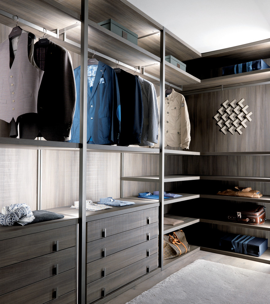 This is an example of a large contemporary gender neutral walk-in wardrobe in Dorset with open cabinets, dark wood cabinets and concrete flooring.