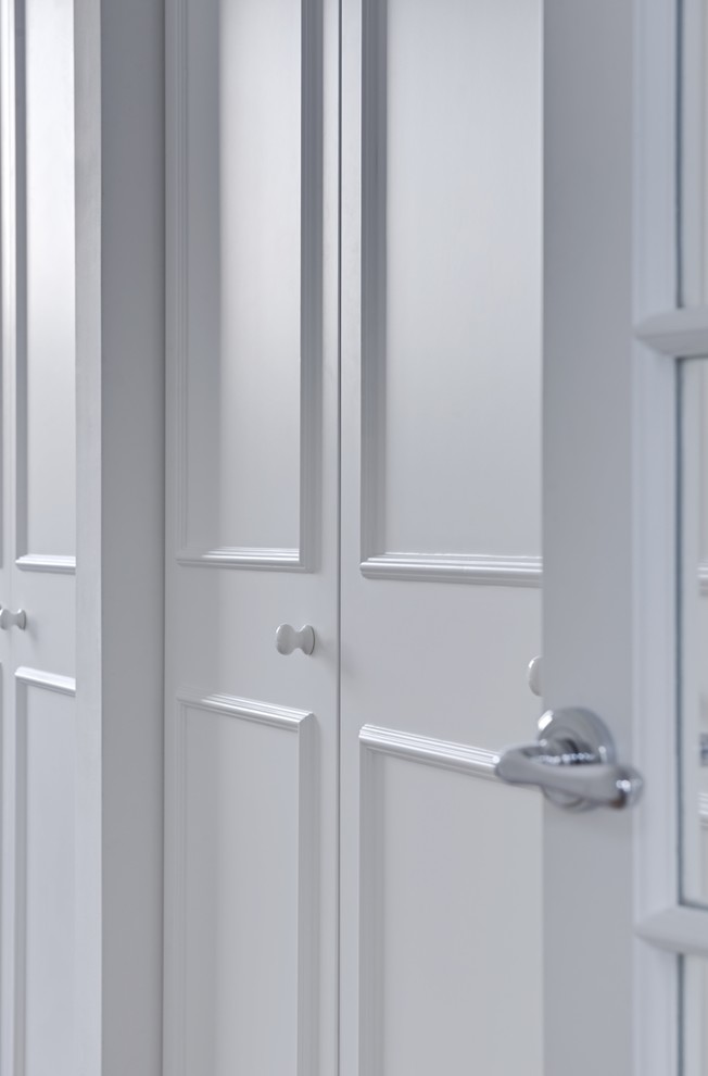 Imagen de armario vestidor unisex clásico pequeño con armarios con paneles empotrados, puertas de armario blancas, suelo de madera clara y suelo marrón