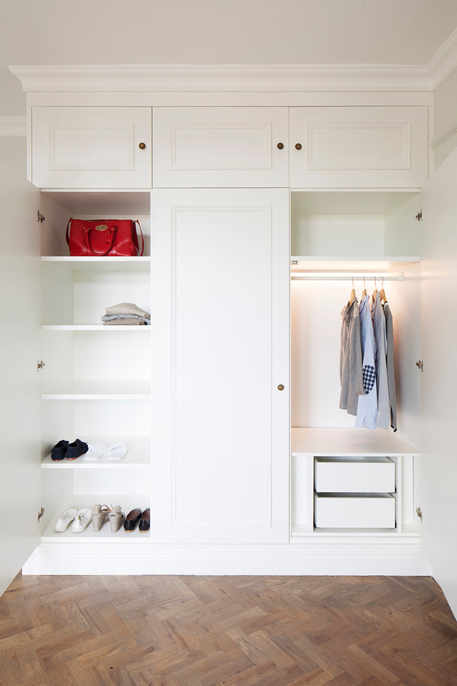 Ejemplo de armario y vestidor unisex tradicional con puertas de armario blancas, suelo de madera en tonos medios y armarios con paneles empotrados