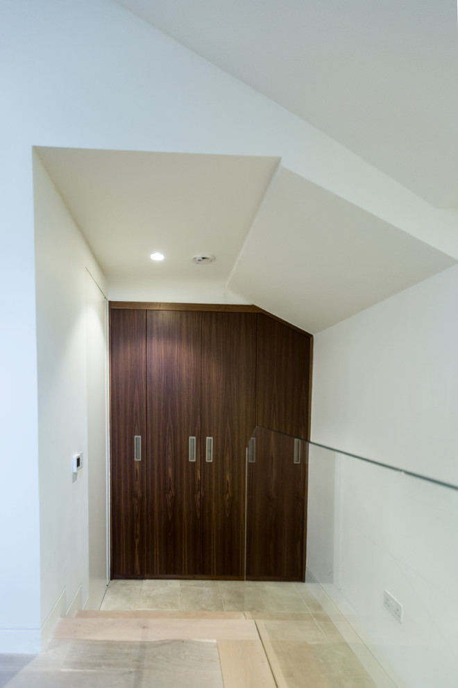 Large contemporary wardrobe in London with dark wood cabinets.