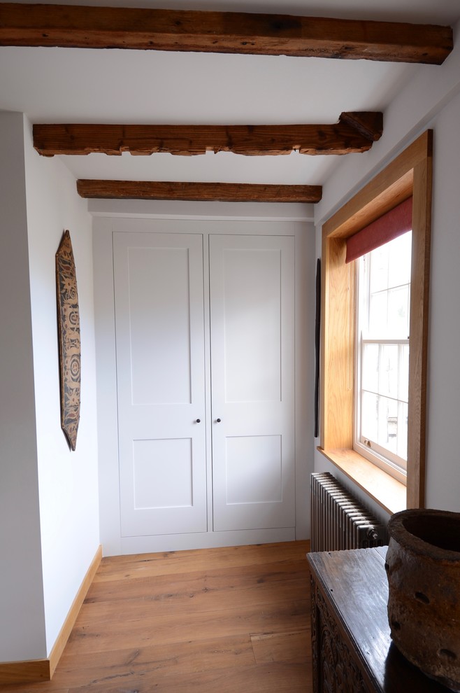 Foto de armario unisex tradicional pequeño con armarios estilo shaker, puertas de armario grises y suelo de madera clara