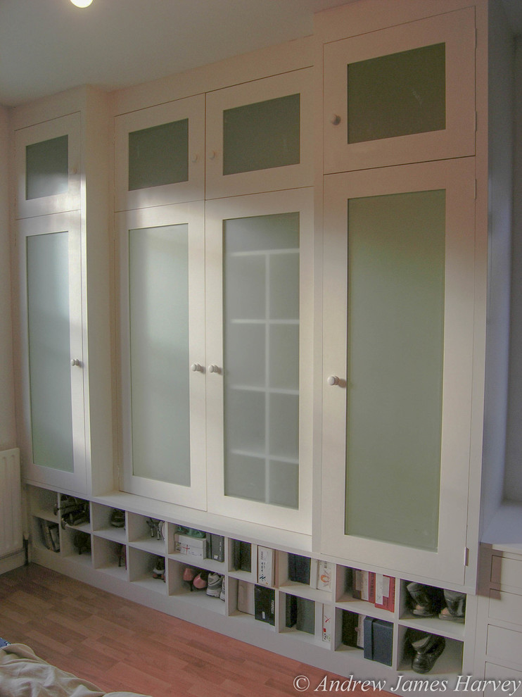 Стильный дизайн: шкаф в нише среднего размера, унисекс в современном стиле с стеклянными фасадами, белыми фасадами и паркетным полом среднего тона - последний тренд