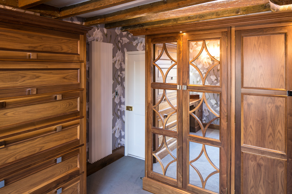 Imagen de vestidor unisex campestre pequeño con puertas de armario de madera oscura y moqueta
