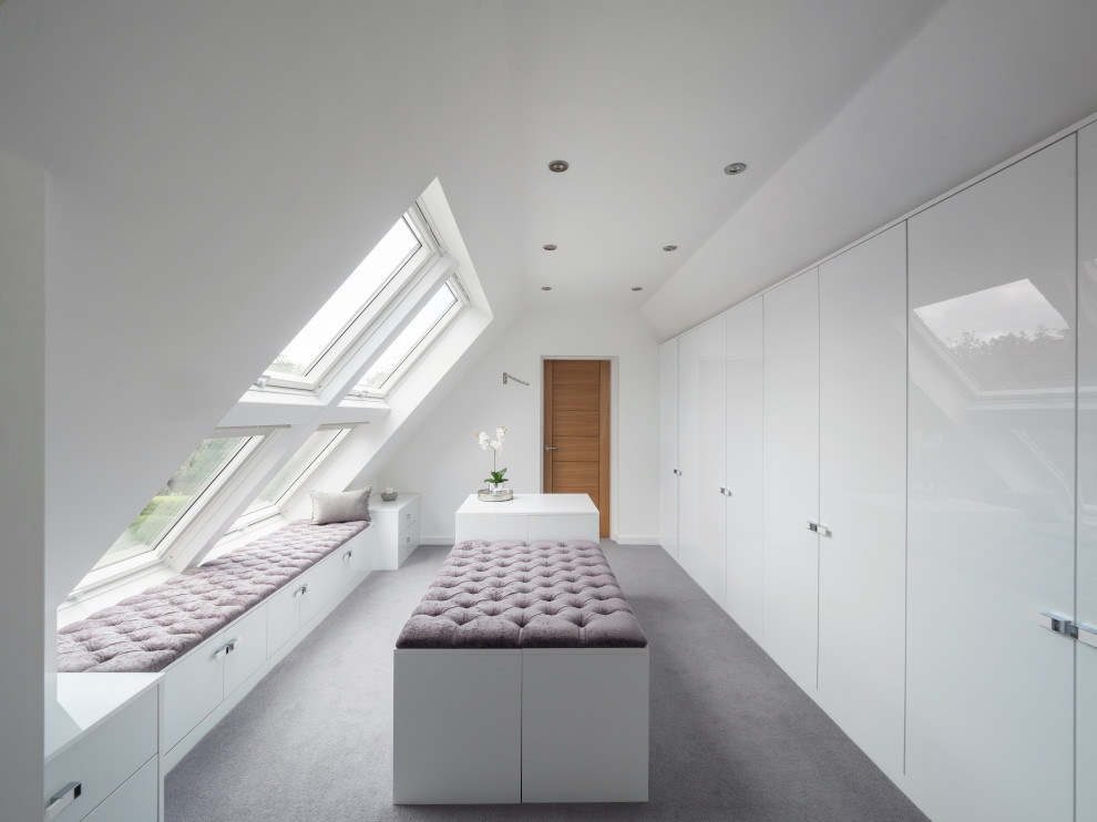 Mittelgroßes, Neutrales Modernes Ankleidezimmer mit Ankleidebereich, flächenbündigen Schrankfronten, weißen Schränken, Teppichboden und grauem Boden in West Midlands