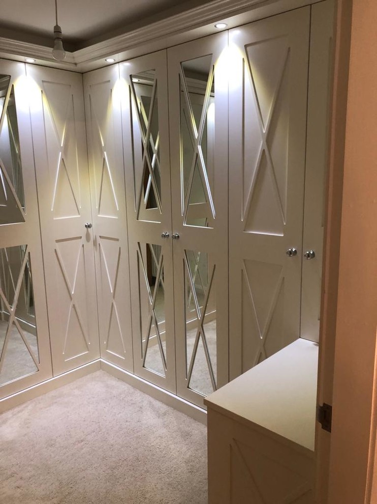 This is an example of a small contemporary gender neutral dressing room in Other with white cabinets, carpet and beige floors.